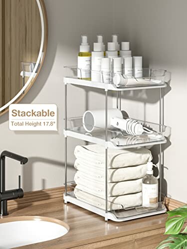 Three-tier bathroom organizer with toiletries and towels on a wooden counter.