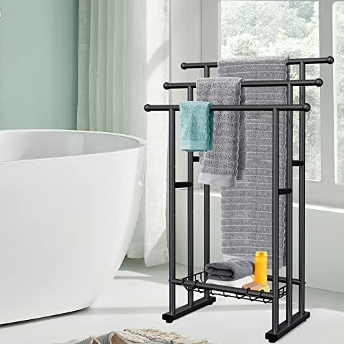 Black towel rack with towels beside a bathtub