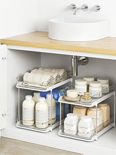 Neatly organized under-sink storage with shelves holding towels and various bottles.